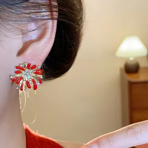 Primo piano di un orecchino a forma di fuochi d'artificio con smalto rosso e strass