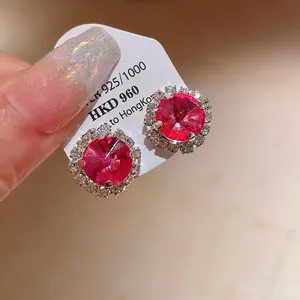 Detailed macro shot of elegant silver round stud earrings featuring red crystals and halos