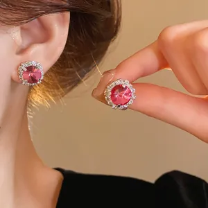 Macro detail of elegant pink crystal round stud earrings with shimmering halo diamond