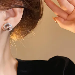 Detailed close-up of a sparkling round diamond-set stud earring worn on a model ear