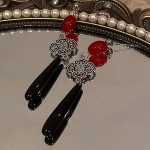 Detail view of New Chinese style earrings with red beads and black teardrop pendants