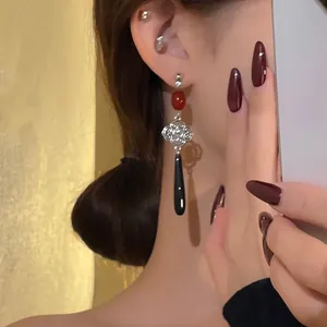 Close-up of neo-Chinese style long water-drop earrings with silver knot and red bead