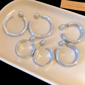 Detailed view of silver thick C-shaped hoop earrings with ball stud closure on a tray