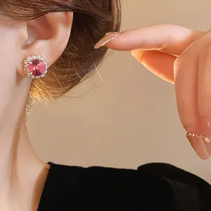 Macro view of elegant pink round gemstone stud earrings with a crystal halo on a model