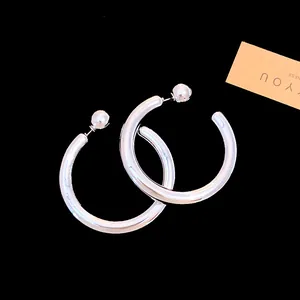 Close-up of minimalist silver C-shaped hoop earrings with a high-shine metallic finish