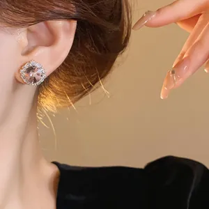Close-up of elegant floral crystal rhinestone stud earring on ear with warm ambient lighting.