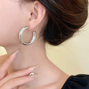 Detailed close-up showing a thick silver-toned C-shaped hoop earring on a model.