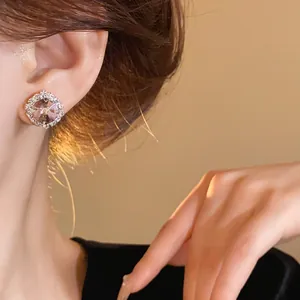 Close-up of an elegant round pink crystal halo stud earring worn on a model's ear