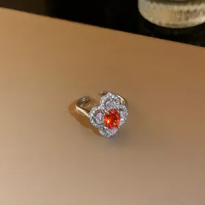 Gros plan d'une bague argentée ajustable avec zircon orange ovale et détails floraux