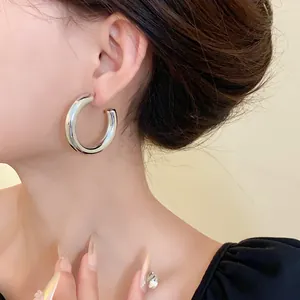 Close-up detail of a minimalist silver C-shaped hoop earring worn on an ear for elegant style.