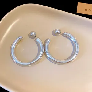 Close-up of silver-tone C-shaped hoop earrings with ball stud back details