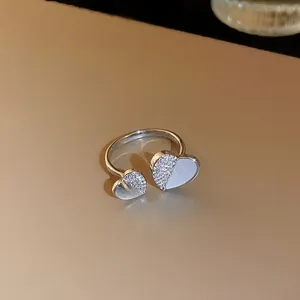 Vue détaillée d'une bague ouverte en cœur avec zircons et incrustation blanche