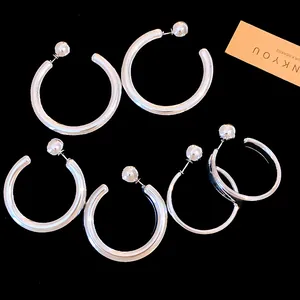 Detailed macro view of silver C-shaped hoop earrings with ball stud two-way design