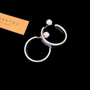 Close-up of minimalist silver-tone C-shaped hoop earrings with elegant pearl accents.
