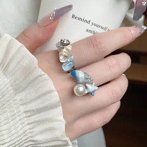 Primo piano di un anello aperto a tema oceano con zircone, perla e stella marina