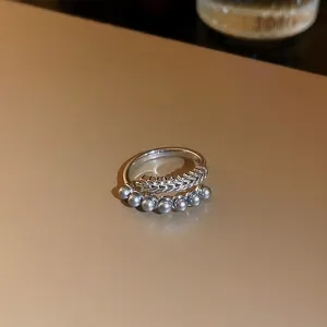 Détail rapproché d'une bague dragon argentée avec d'élégantes perles grises.
