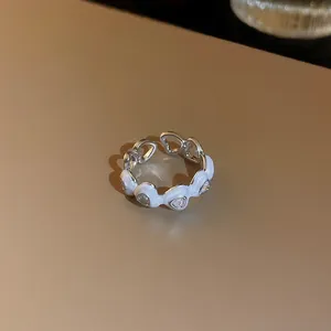 Détail d'une bague ouverte en émail blanc en forme de cœur avec des zircons brillants