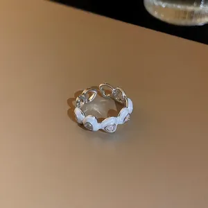 Gros plan sur une bague ajustable argentée avec cœurs en émail blanc et zircons clairs