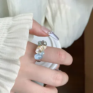 Primo piano dettagliato di anello aperto con conchiglia, pietre azzurre e perle