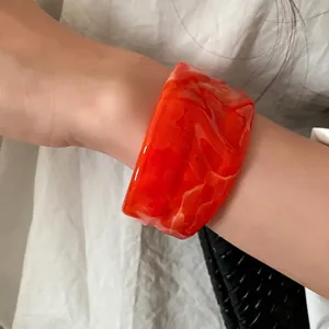Elegant orange marbled pleated open bangle bracelet for women, lifestyle wrist display shot