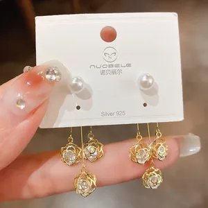 Close-up of gold-plated hollow floral drop earrings with sparkling cubic zirconia stones