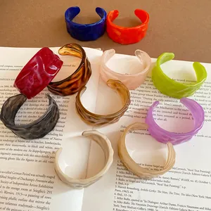 Premium collection of colorful textured acrylic open cuff bangles displayed on a book