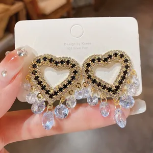 Close-up detail of heart-shaped earrings with black crystals and dangling beads.