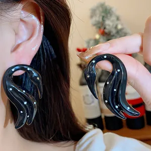 Primer plano de pendientes de cisne negro con diseño de lunares en la oreja de modelo