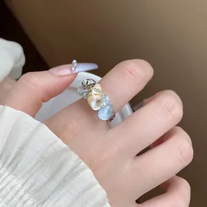 Primo piano di un anello aperto alla moda con vera conchiglia, perle e pietre blu