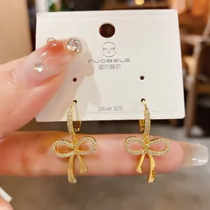 Macro detail view of elegant gold-plated cubic zirconia bow-knot hoop earrings