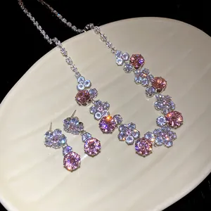 Close-up of pink and clear zircon flower necklace and earring set on a display plate