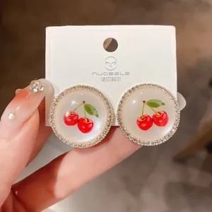 Macro view of sweet cherry earrings featuring sparkling rhinestone borders on display.