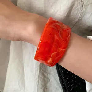 Close-up of orange marble swirled resin bangle with a unique wrinkled surface texture
