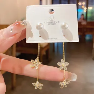 Detailed view of elegant gold-plated flower earrings with shimmering zircons and pearls