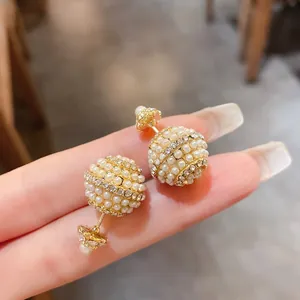 Close-up of elegant gold-plated spherical stud earrings with pearls and rhinestones