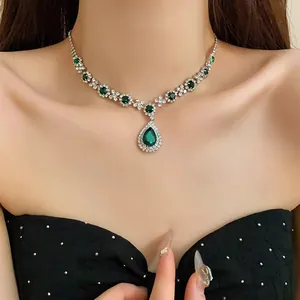 Elegant silver-tone crystal necklace featuring a green emerald teardrop pendant on model
