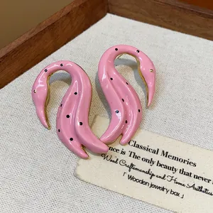 Vista detallada de los pendientes de cisne en esmalte rosa con lunares negros
