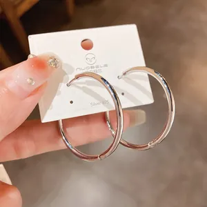 Detailed view of minimalist silver plated hoop earrings displayed on a white brand card