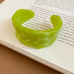 Macro view of a lime green resin cuff bracelet featuring a unique textured pleated design