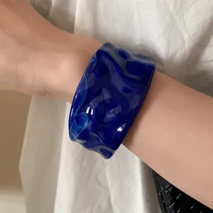 Macro detail view of a premium translucent blue rippled bangle with marble texture on wrist