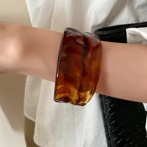 Macro detail showing the marbled amber resin bracelet with elegant pleated texture