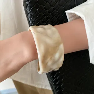 Macro view of a marbled cream resin open bangle showing the unique wrinkled texture design