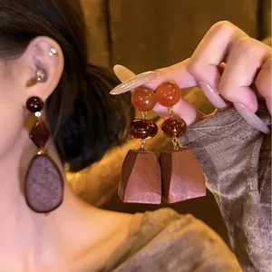 Vintage ethnic style wooden bead earrings with silver needles shown on an Asian model.
