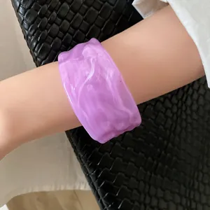 Close-up of a marbled purple resin bangle with irregular pleated texture on wrist.