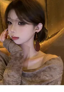 Close-up of a model wearing vintage oval wooden bead earrings with an ethnic design