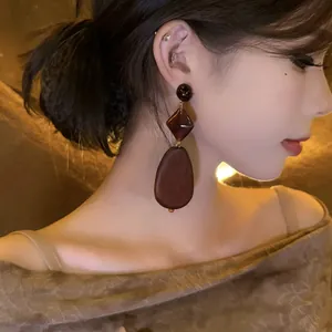 Detailed side view close-up of vintage ethnic style wooden teardrop earrings on model