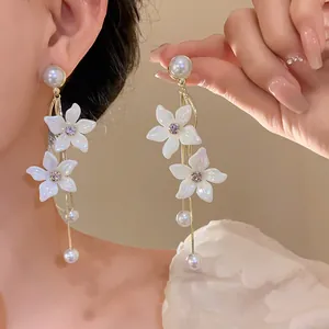 Exquisites Detail von schimmernden Perlen-Ohrringen mit Blumenanhänger an Model