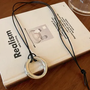 Vue détaillée d'un collier pendentif circulaire minimaliste en argent sur cordon cuir noir