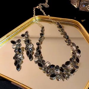 Vue macro d'un collier de luxe en strass noirs et boucles d'oreilles assorties sur plateau doré