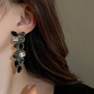 Détail de boucles d'oreilles pendantes avec cristaux scintillants pour un look chic.